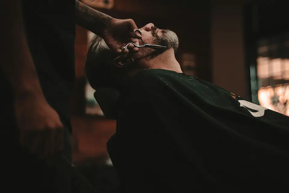 Barber modeluje fryzurę klienta maszynką